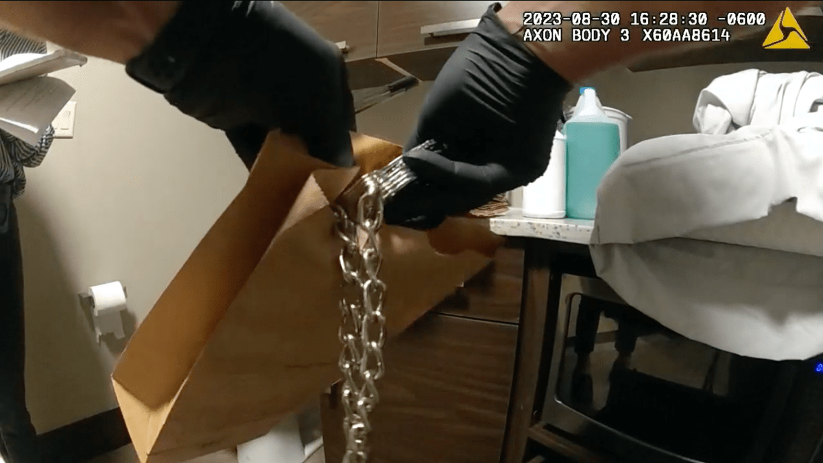 A pair of handcuffs attached to a rope being placed into an evidence bag by a police officer investigating the home of Jodi Hildebrandt.