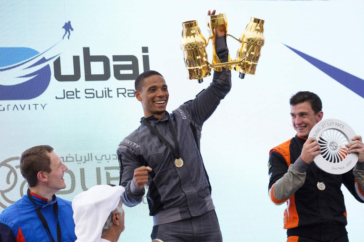Jet suit pilot Issa Kalfon of the United Kingdom, center, waves his trophy after winning a race in Dubai, United Arab Emirates, Wednesday, Feb. 28, 2024. (AP Photo/Jon Gambrell)