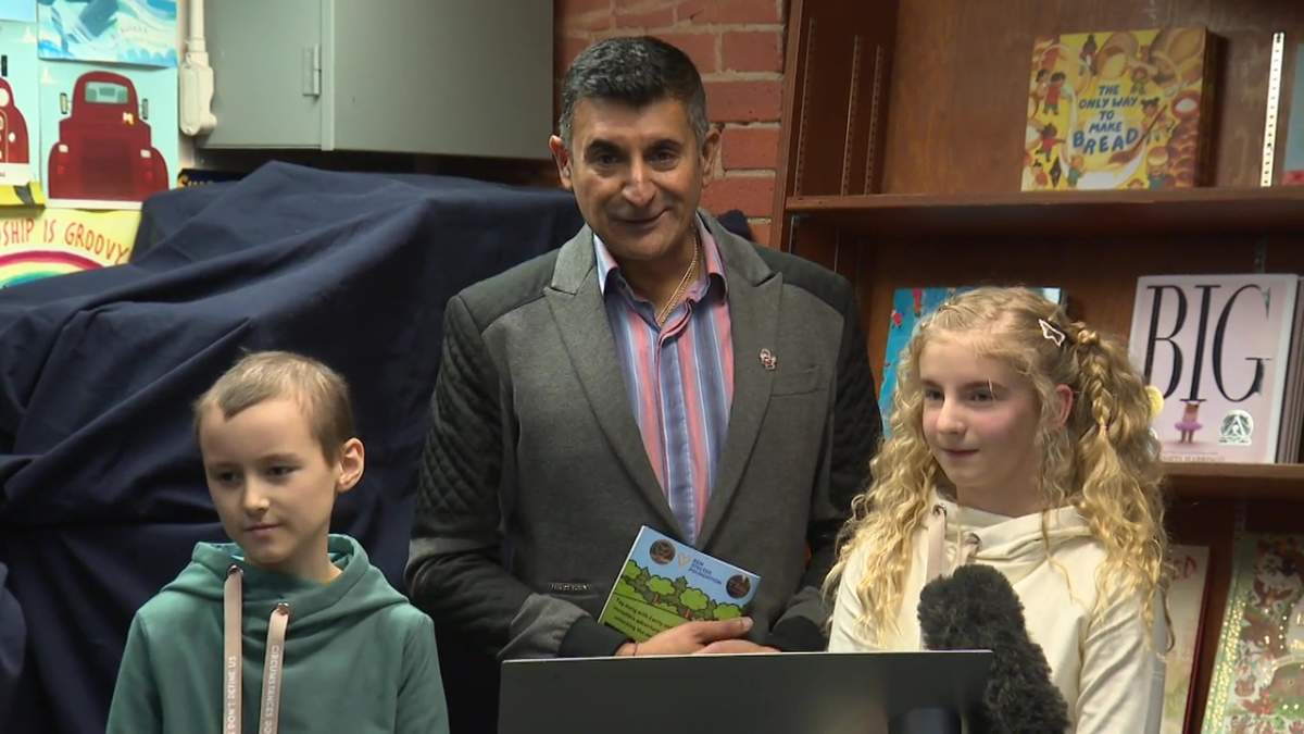 Cosmo Amasio (left), Ashif Mawji (middle), and Cecily Eklund (right) stand together at the launch of their book called, the Kindness Coin.