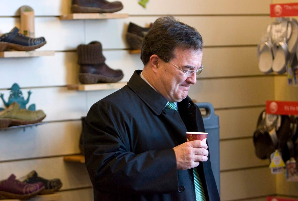 Canada's Finance Minister Jim Flaherty clasps a cup of coffee as he arrives at a shoe store in Whitby Ontario on Monday March 1, 2010.