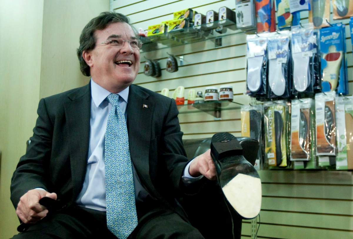 Finance Minister Jim Flaherty holds up his newly re-soled shoes during a pre-budget photo opportunity at Healthy Feet Shoe Repair in Ottawa on Monday, March 21, 2011.