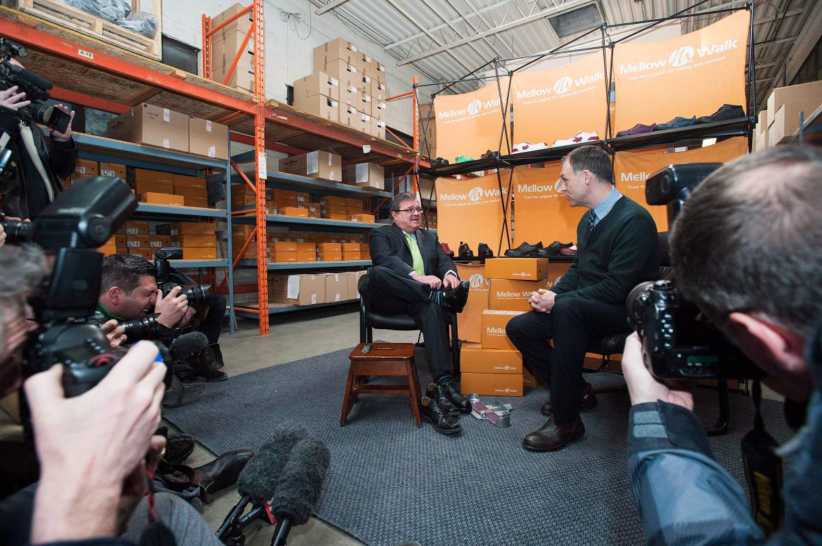 Finance Minister Jim Flaherty tries on a pair of shoes with Andrew Violi president of Mello Walk Shoes at a pre-budget press event in Toronto on Friday February 7, 2014.