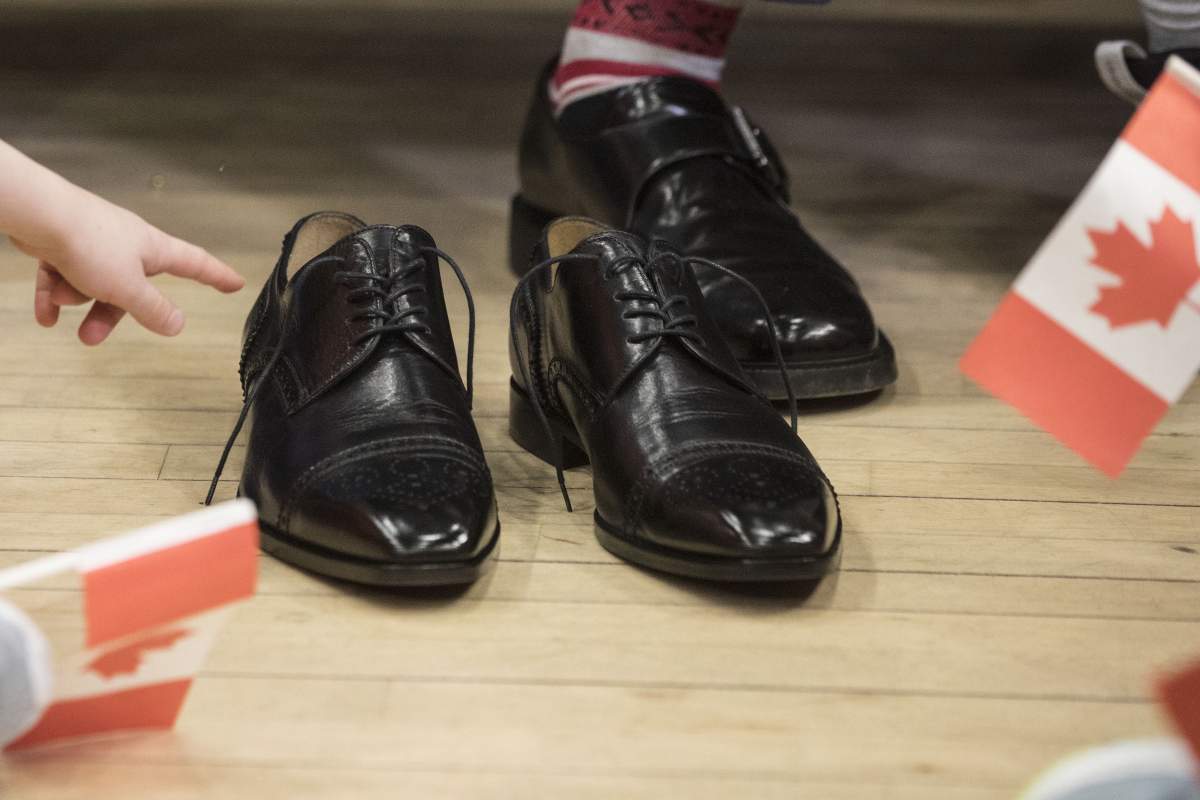 A child points to the new budget shoes being put on by Federal Finance Minister Bill Morneau in a pre-budget photo opportunity in Toronto on Thursday, March 14, 2019.