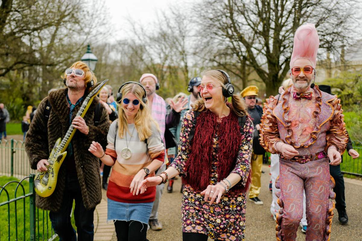 People dressed in costumes take part in a silent disco event outside the Brighton Dome, in Brighton, England, Saturday, April 6, 2024. Fans are celebrating 50 years since ABBA won its first big battle with “Waterloo.”