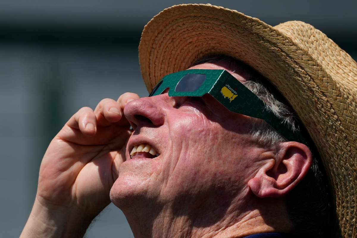 A patron look up at the sun during an solar eclipse during a practice round in preparation for the Masters golf tournament at Augusta National Golf Club Monday, April 8, 2024, in Augusta, Ga. (AP Photo/Matt Slocum)