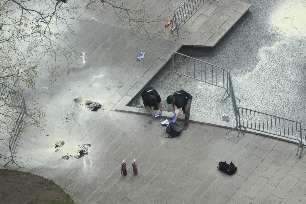 New York Police officers inspect a backpack left at the scene where a man lit himself on fire in a park outside Manhattan criminal court, Friday, April 19, 2024, in New York. Emergency crews rushed away a person on a stretcher after fire was extinguished outside the Manhattan courthouse where jury selection was taking place in former President Donald Trump’s hush money criminal case. (AP Photo/Mary Altaffer)