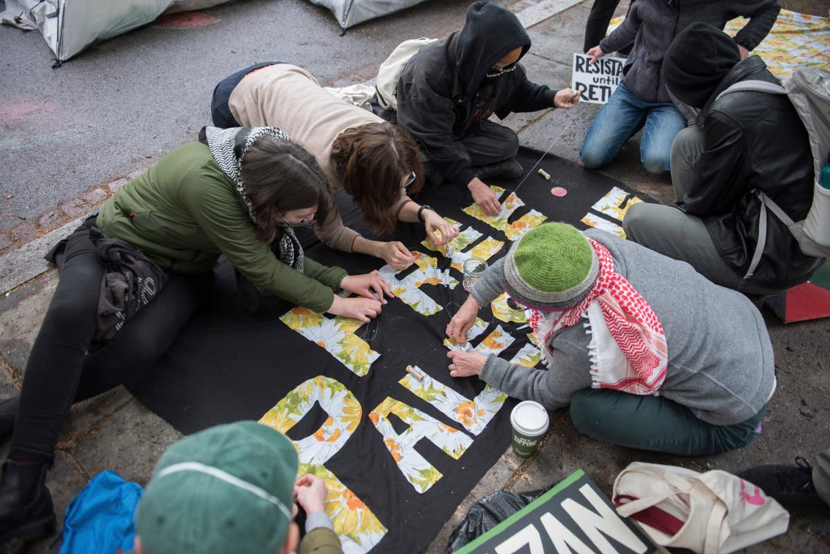 Students protesting the Israel-Hamas war at George Washington University sew a banner in Washington, Saturday, April 27, 2024.