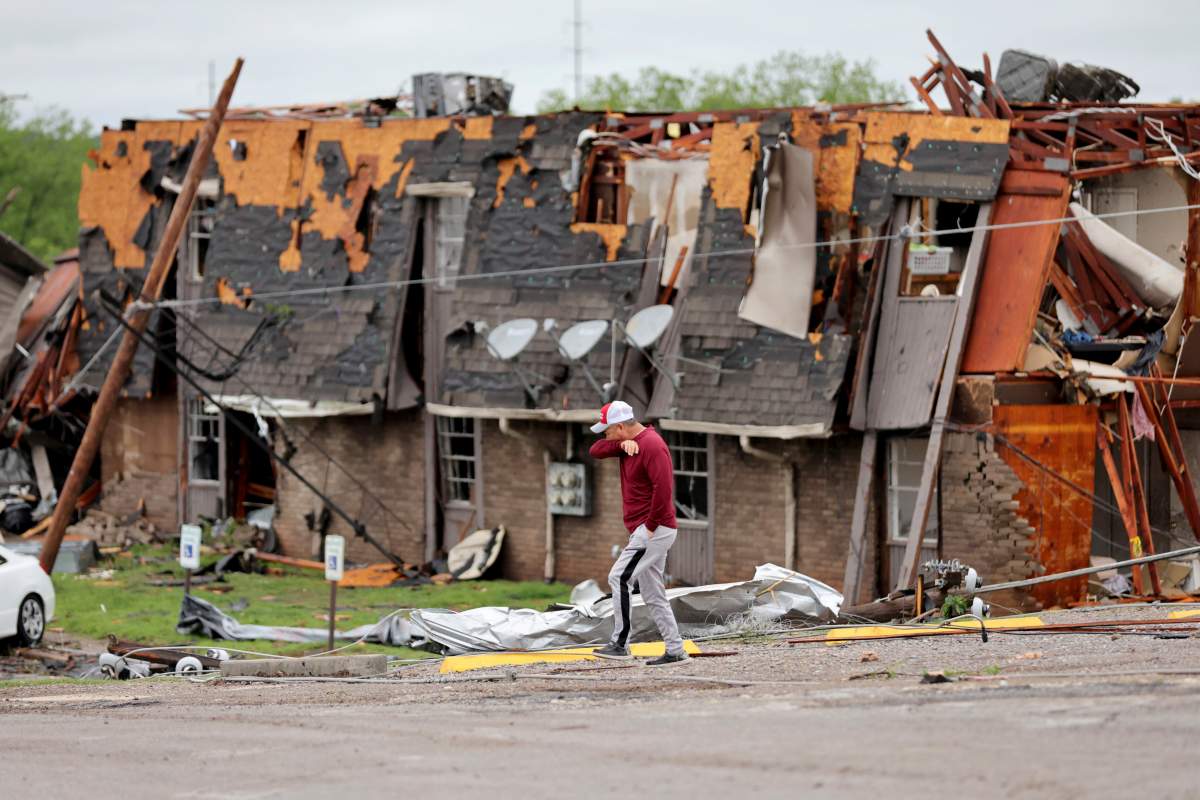 A man walks past tornado damage in Sulphur, Okla., Sunday, April 28, 2024, after severe storms hit the area the night before.