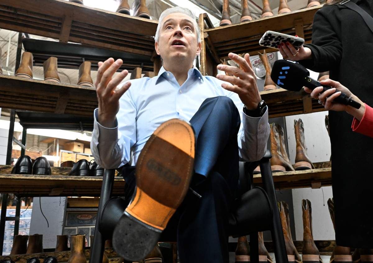Federal Finance Minister Francois Philippe Champagne shows his new shoes he will wear for the budget speech while participating at the making of the shoes, at the Boulet boot factory in St-Tite Que., on Monday, Nov. 3, 2025.