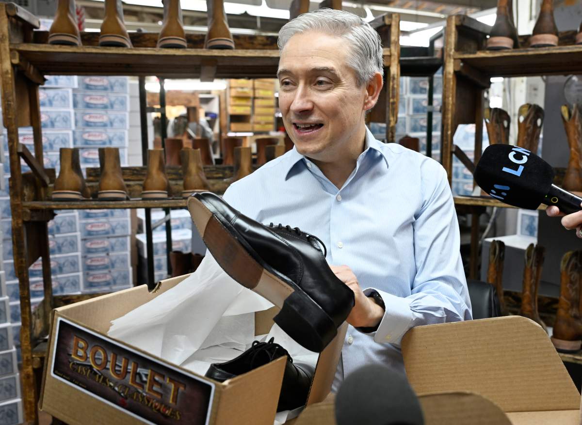 Federal Finance Minister Francois Philippe Champagne shows his new shoes he will wear for the budget speech while participating at the making of the shoes, at the Boulet boot factory in St-Tite Que., on Monday, Nov. 3, 2025.