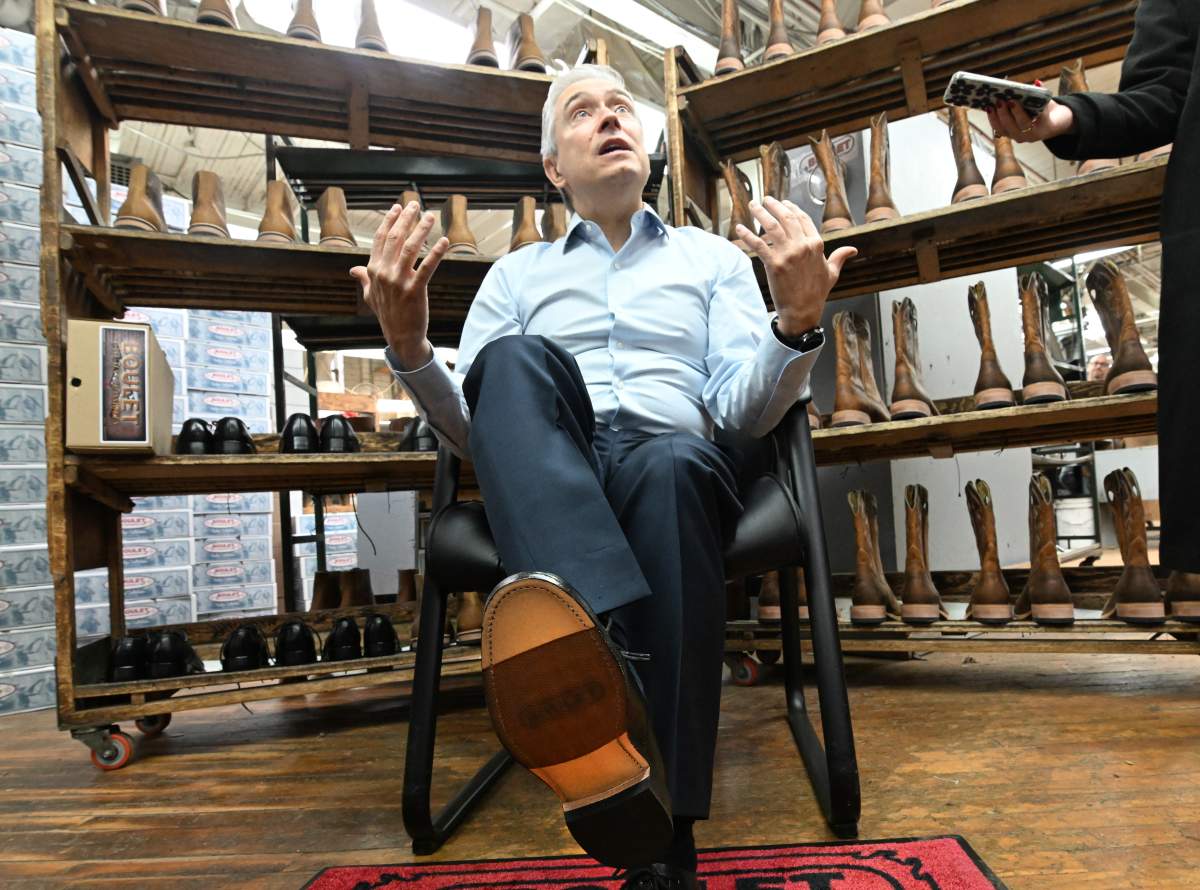 Federal Finance Minister Francois Philippe Champagne shows his new shoes he will wear for the budget speech while participating at the making of the shoes, at the Boulet boot factory in St-Tite Que., on Monday, Nov. 3, 2025.