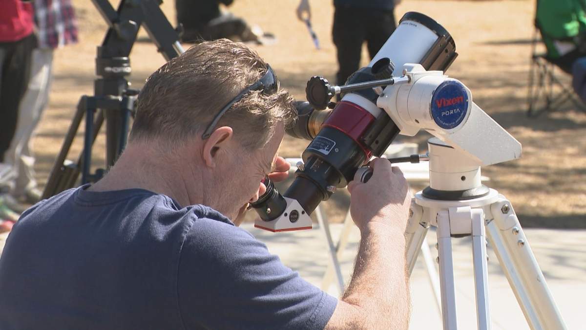 A Regina resident looks through a telescope at the solar eclipse.
