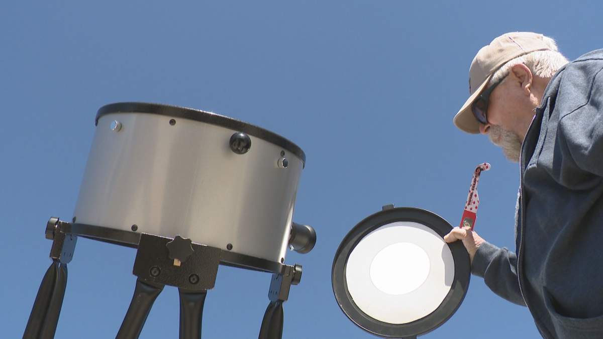 A man sets up a telescope to observe the solar eclipse.