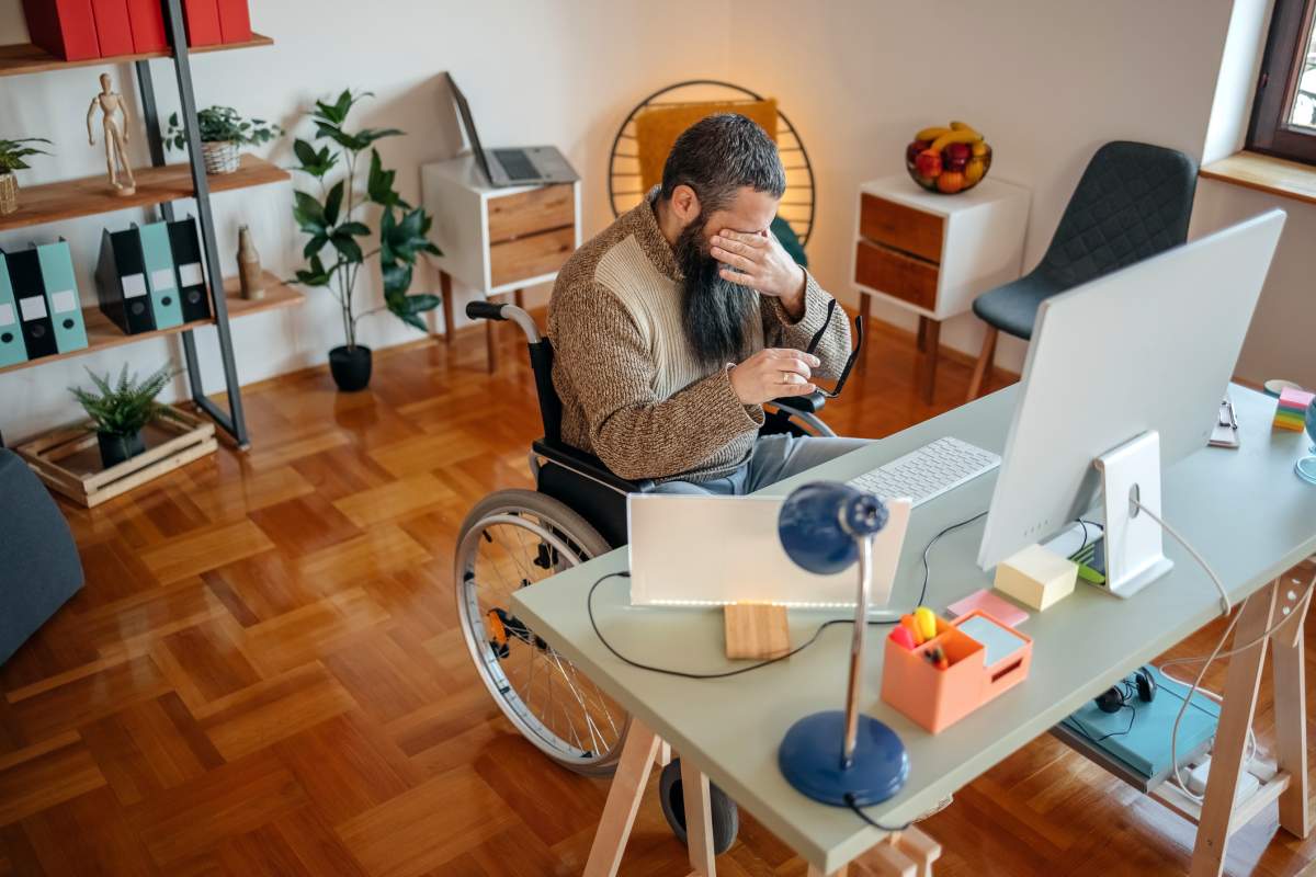 Person with disability working home office in wheelchair using computer