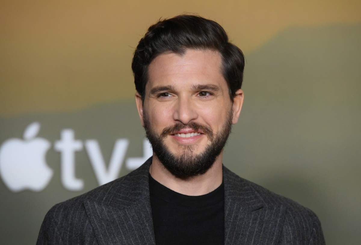 Kit Harington. He is wearing a dark blazer. He is smiling.