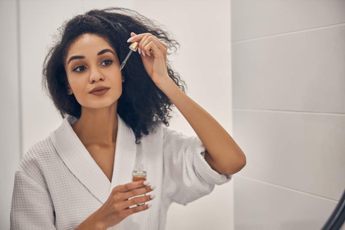 Woman applying serum to her face while getting ready