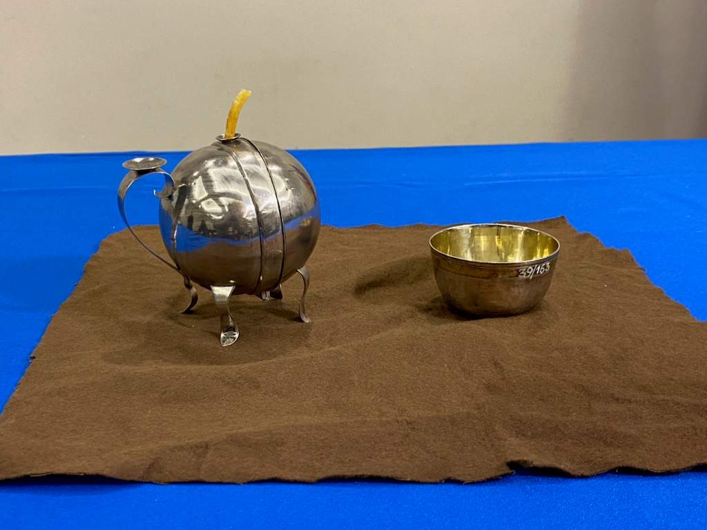 Two silver items on a brown cloth on a blue table.