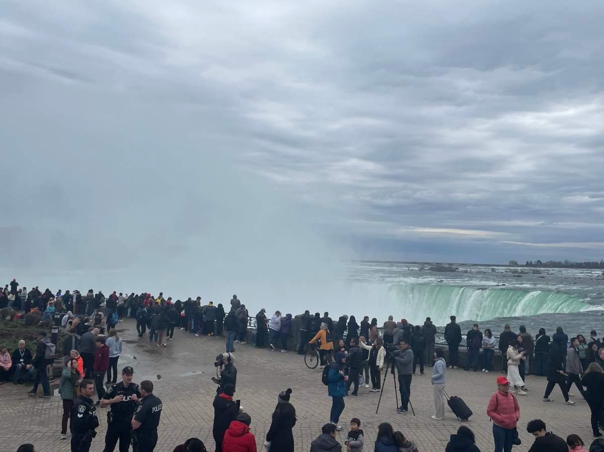 Crowds gathered are a waterfall on a cloudy day.