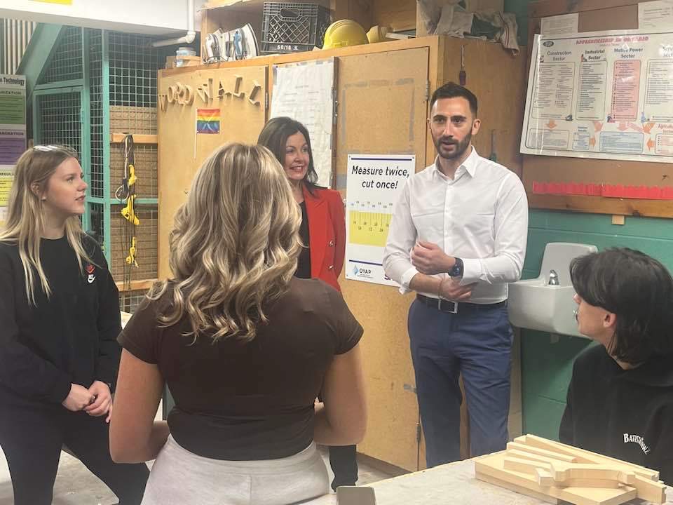 A man and woman in a classroom with three students.