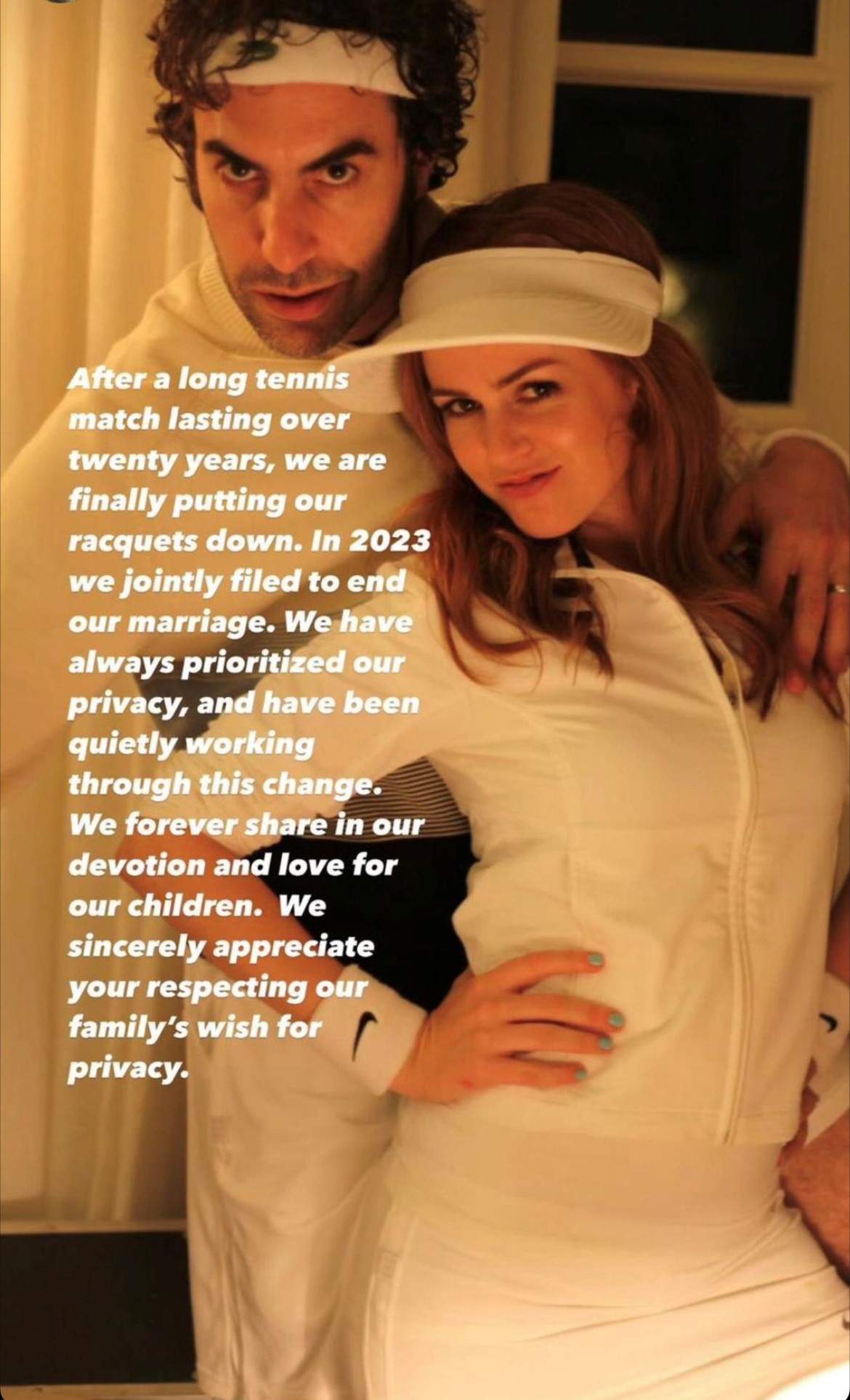 An image of Sacha Baron Cohen and Isla FIsher in white tennis gear, posing for the camera. White text is overlayed.
