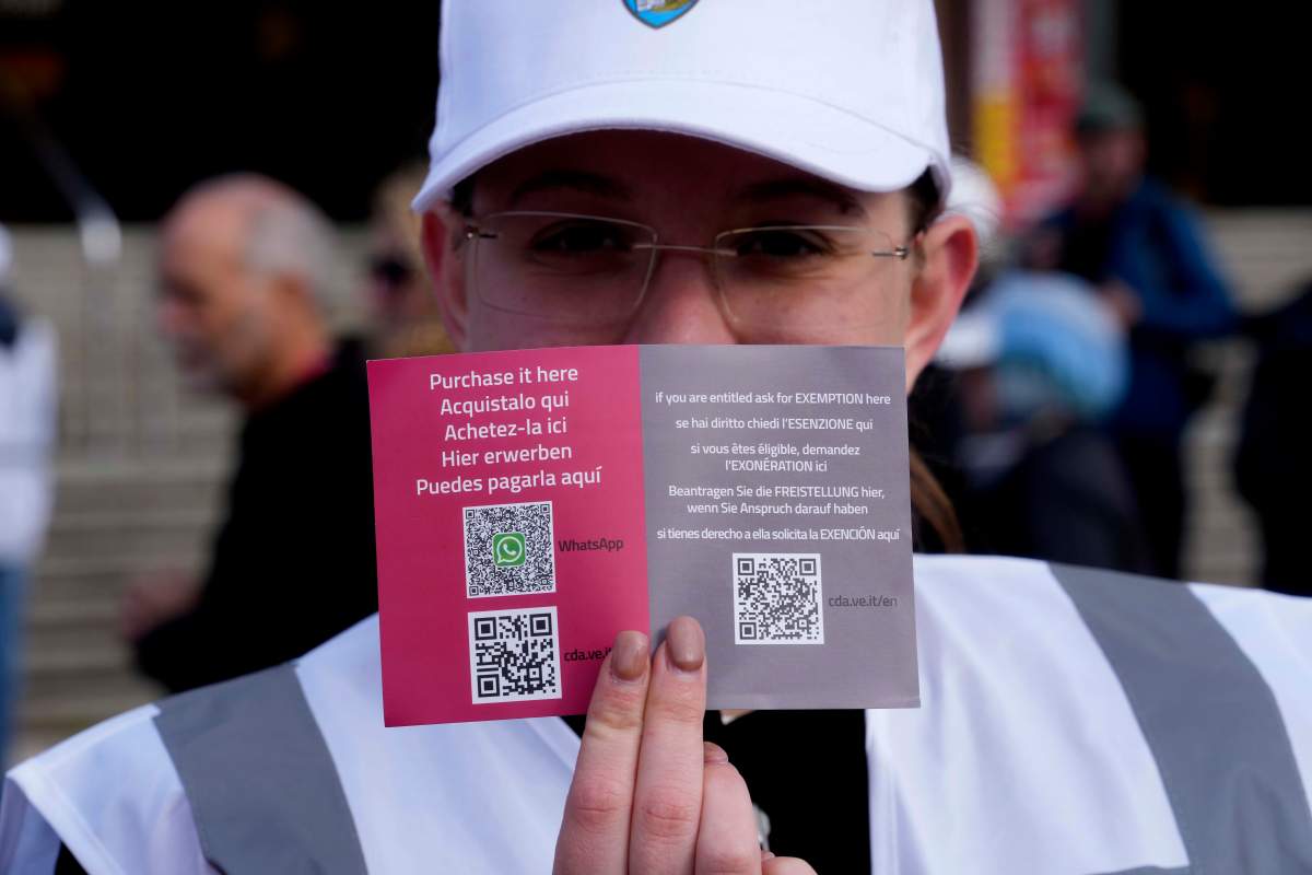 A steward shows the QR code access outside the main train station in Venice, Italy, Thursday, April 25, 2024. (AP Photo/Luca Bruno)
