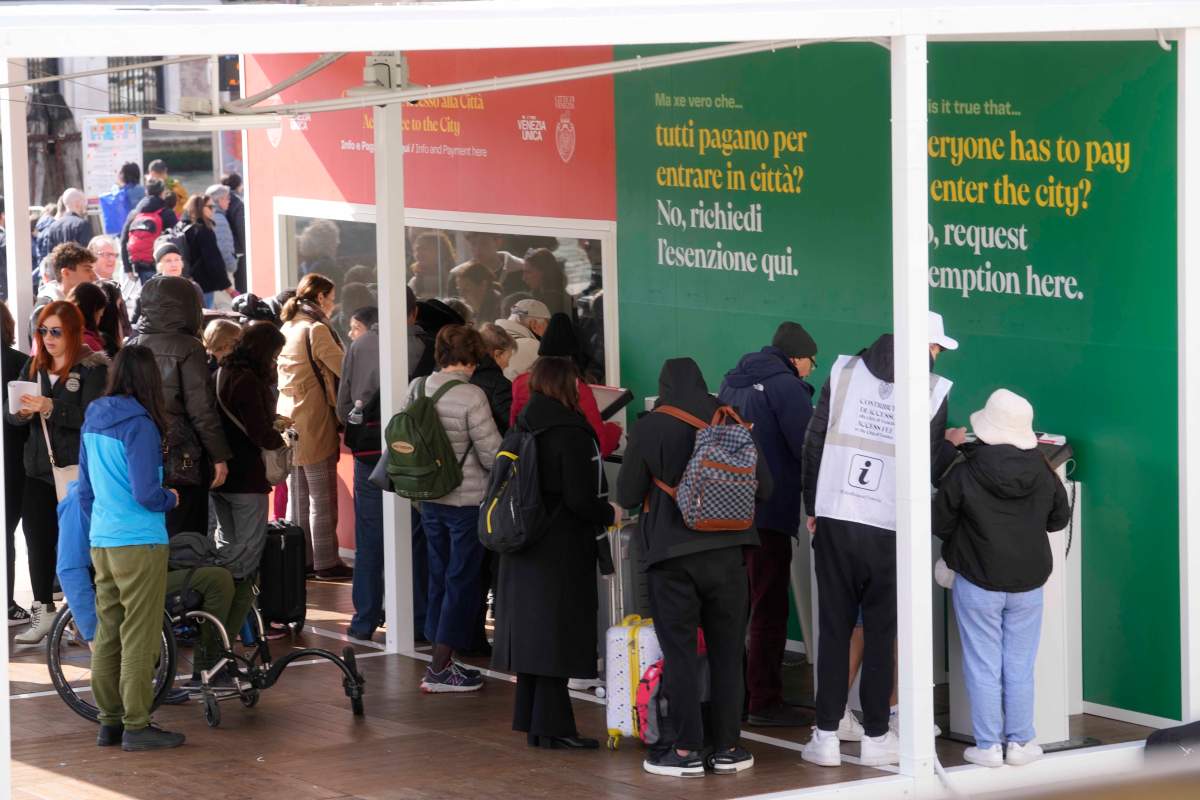 Tourists line up at a cashier buying a QR code fee access upon their arrival at the main train station in Venice, Italy, Thursday, April 25, 2024. (AP Photo/Luca Bruno)