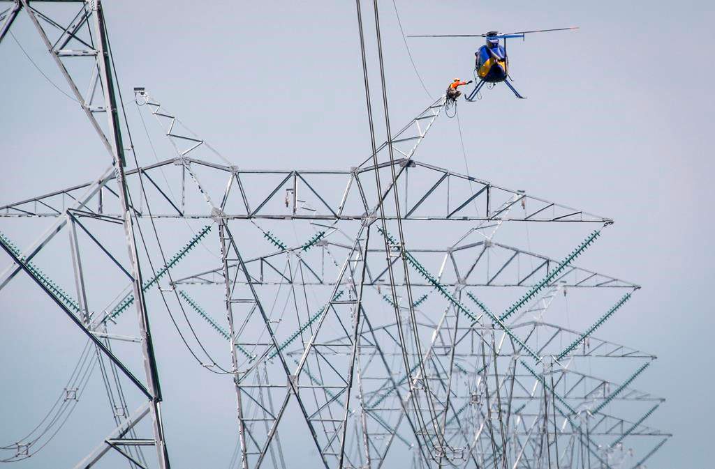 The Saskatchewan and Alberta governments have signed a memorandum of understanding to share information about nuclear power generation. A lineman reaches for a lift from a helicopter as work continues on twinning power lines that run from Calgary to Edmonton near Carstairs, Alta., Wednesday, July 23, 2014.THE CANADIAN PRESS/Jeff McIntosh.