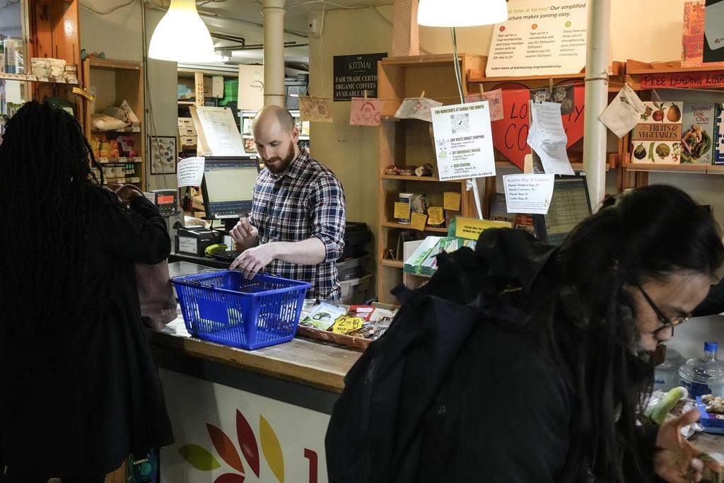 Karma co-op store manager Zachary Weingarten helps members cash out their groceries