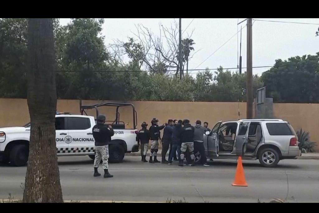 In this image made from video, Mexican security forces frisk men at a checkpoint in Ensenada, Mexico, Thursday, May 2, 2024. Mexican authorities said Thursday they have found tents and questioned a few people in the case of two Australians and an American who went missing over the weekend in the Pacific coast state of Baja California.