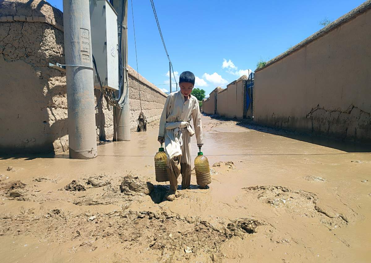 An Afghan boy carries oil through muddy water, after heavy flooding in Baghlan province in northern Afghanistan Sunday, May 12, 2024.  (AP Photo)