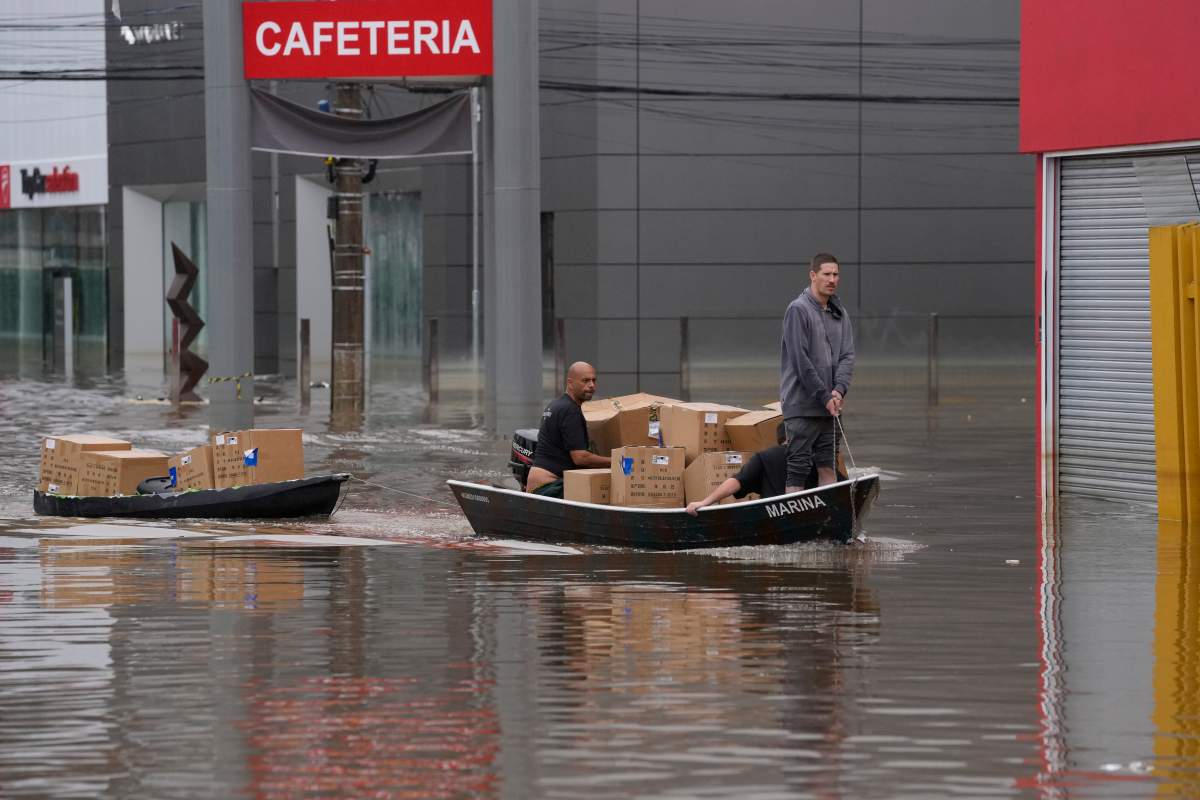Volunteers transport donated supplies through a flooded street after heavy rains in Porto Alegre, Rio Grande do Sul state, Brazil, Sunday, May 12, 2024. (AP Photo/Andre Penner)