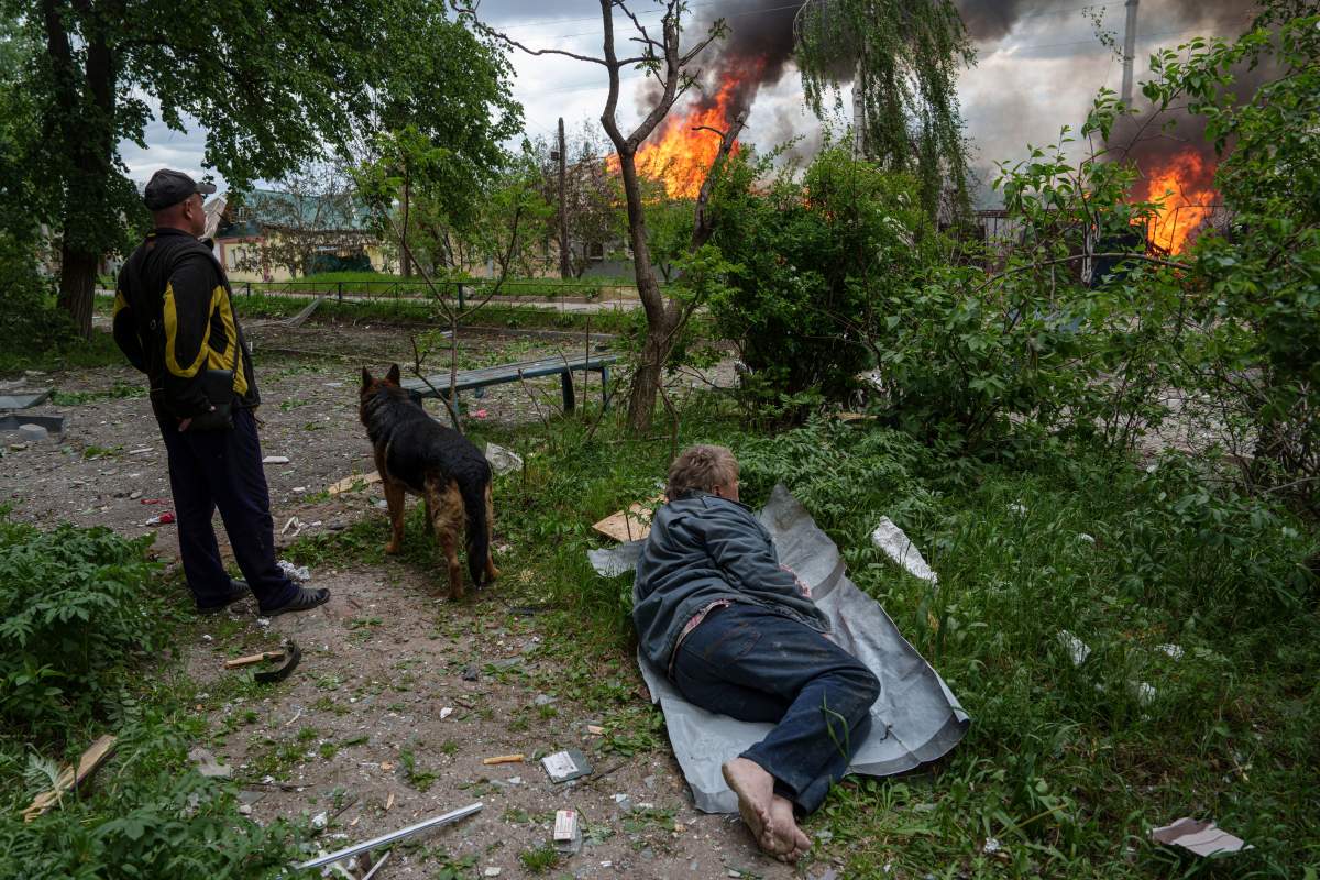 A man lies on the ground as he watches his burning house destroyed by a Russian airstrike in Vovchansk, Ukraine, on Saturday, May 11, 2024.