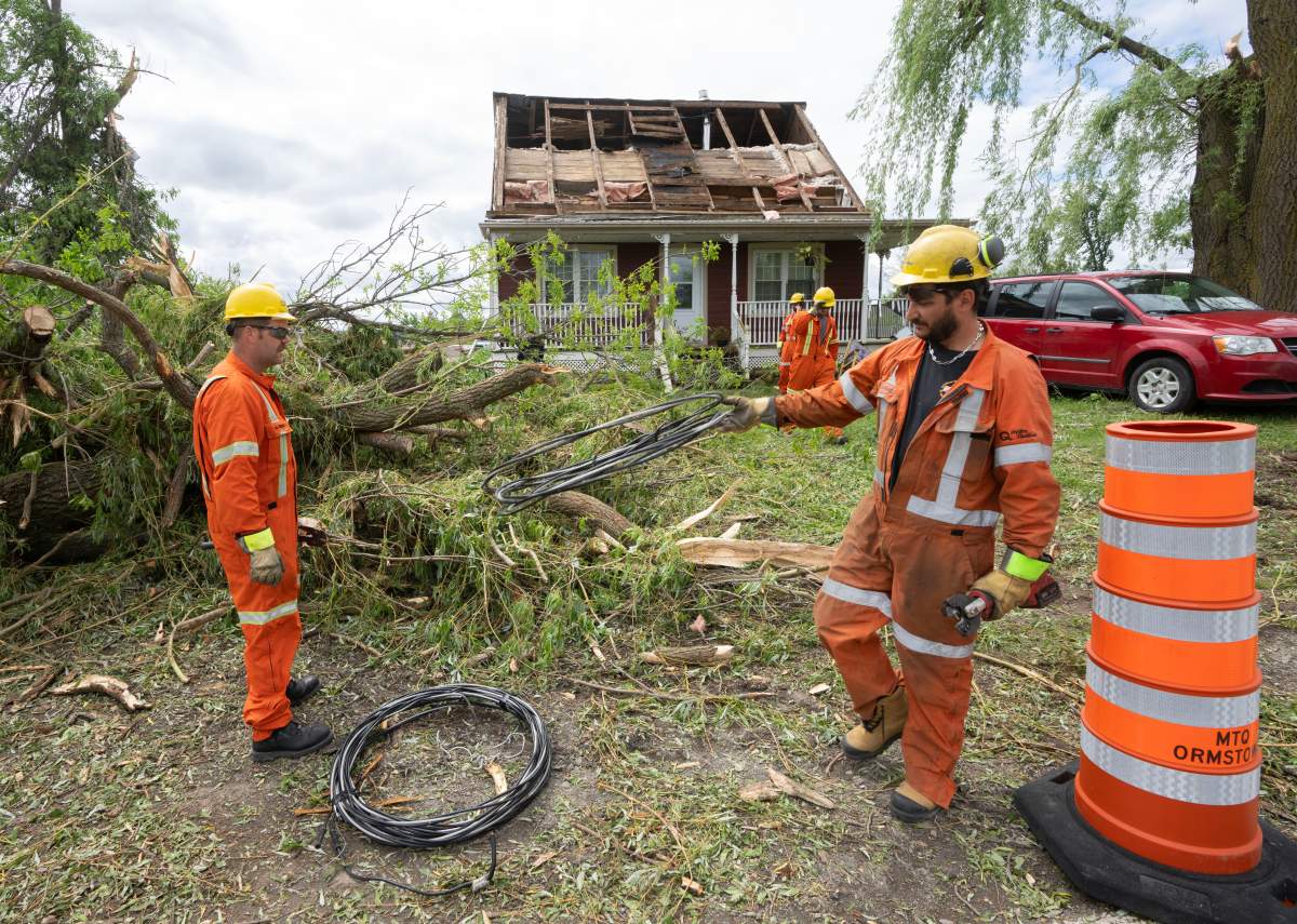 Hydro workers clear downed wires in Tres-Saint-Redempteur, Quebec on Tuesday, May 28, 2024 after a suspected tornado went through yesterday evening.