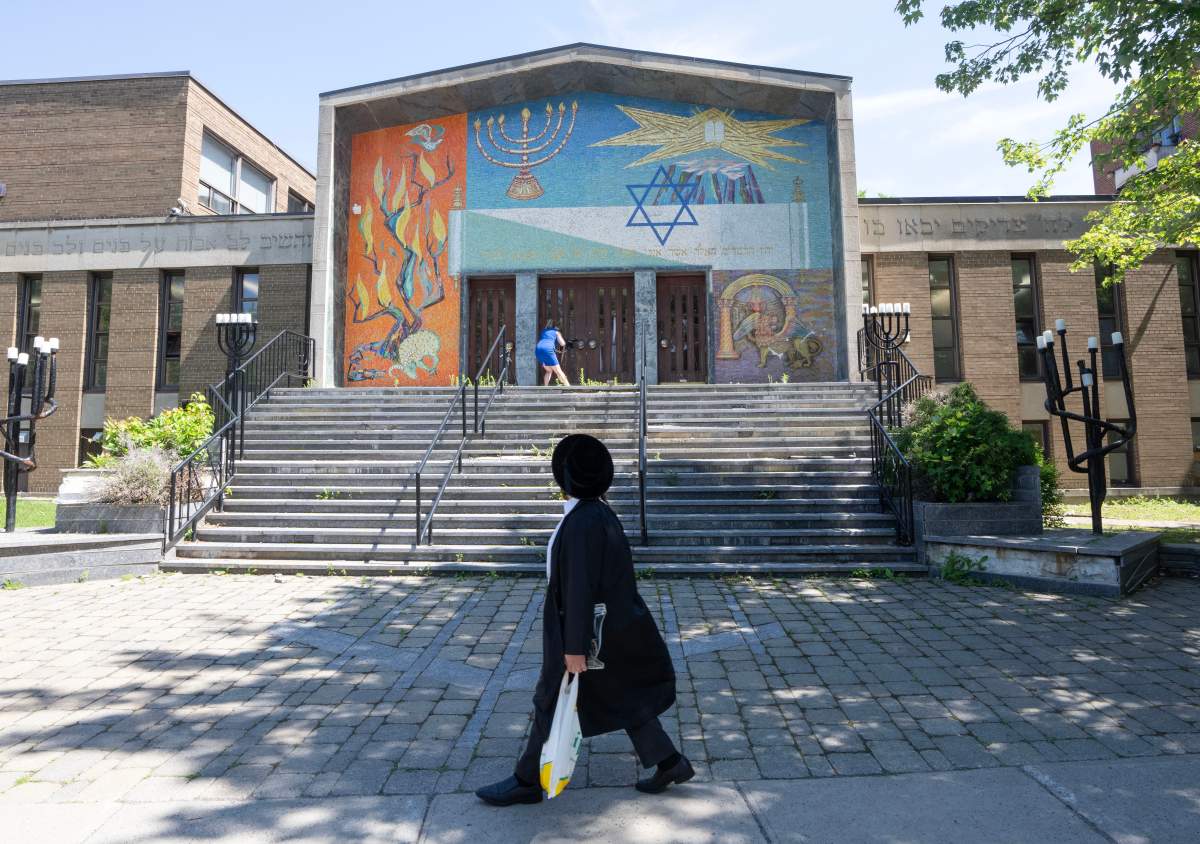 A man walks past the Bell Yeshiva Katana school in Montreal on Thursday, May 30, 2024. Police are investigating after shots were fired at the building.