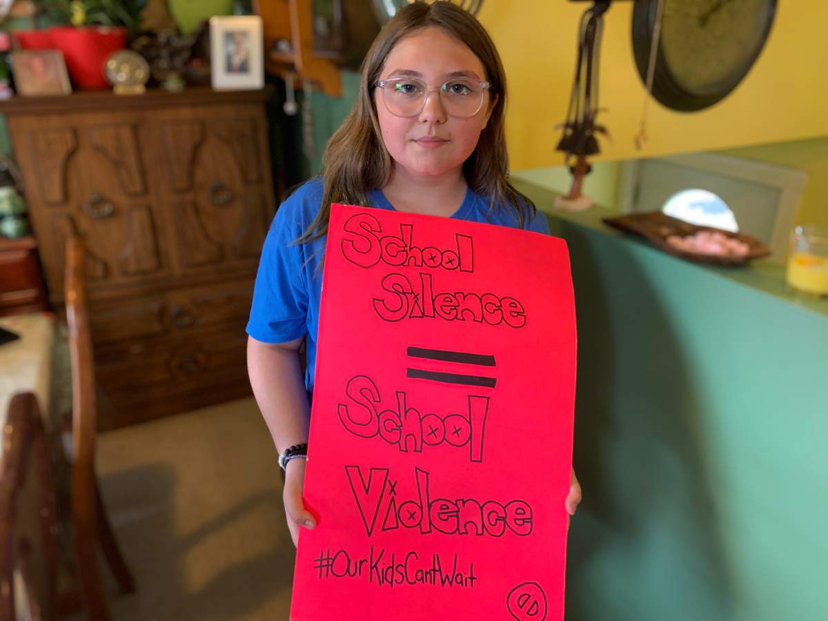 Kaiya Robicheau holds up another one of her signs that she brought to protest outside of her junior high school last week.