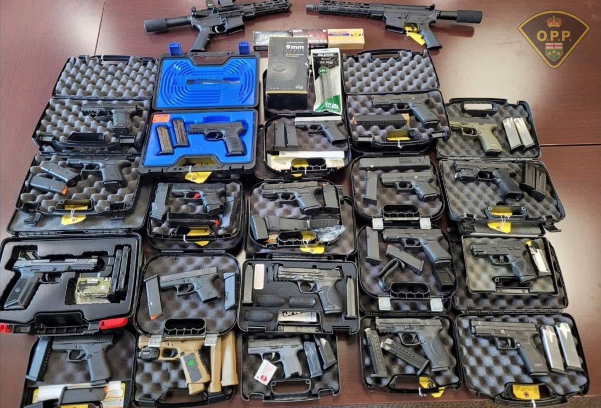 Firearms in open cases on top of a wooden table.