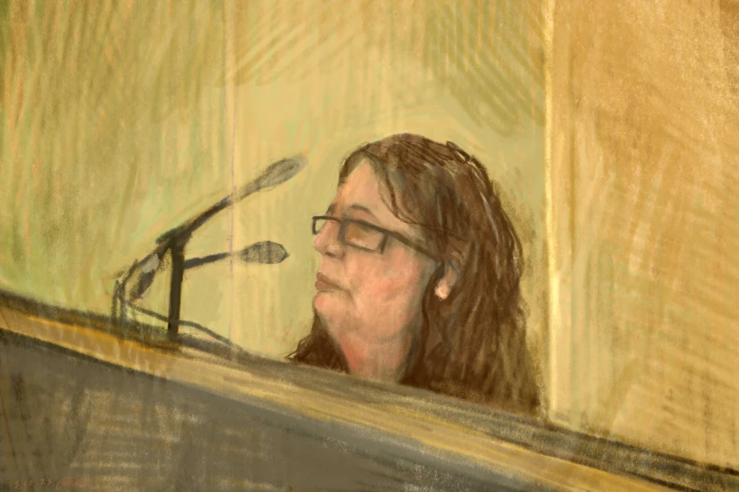 A courtroom sketch of a woman in front of a microphone. Most of her is concealed. She has brown hair and is wearing glasses.