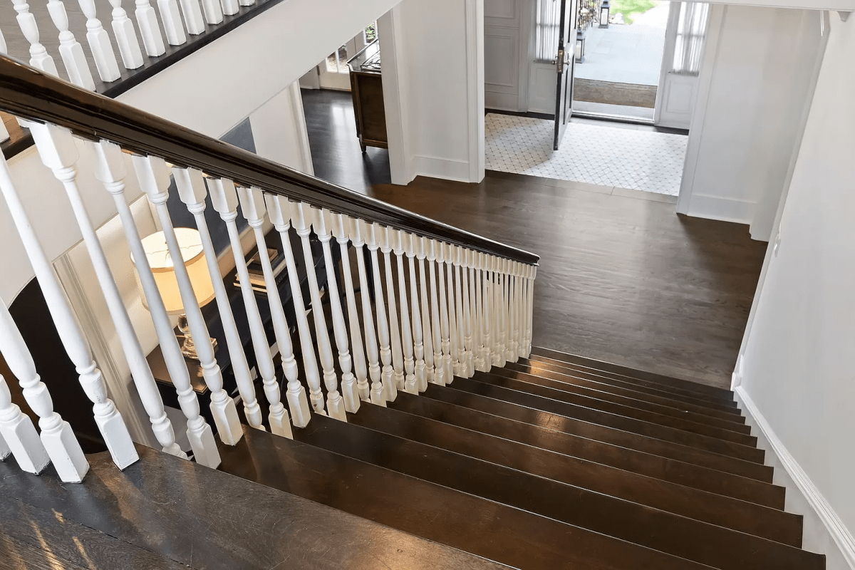 A wooden staircase, leading to a front entrance where the door is open.