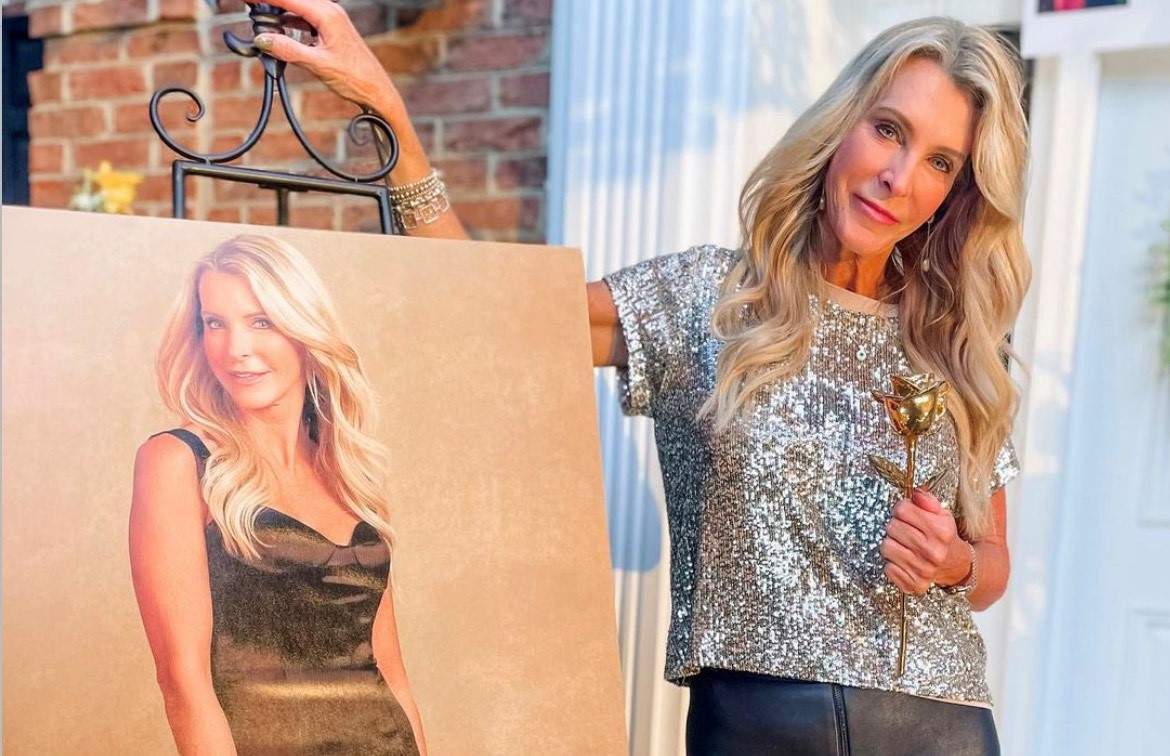 Joan Vassos, standing next to a poster of her 'Golden Bachelor' promotional image.