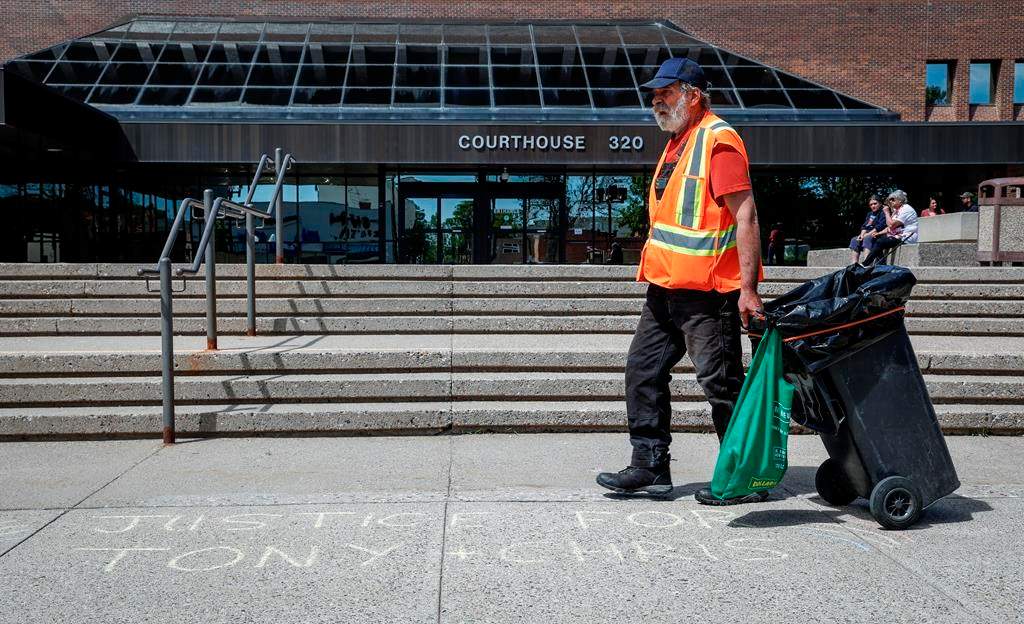 A jury is hearing evidence from two undercover officers in the trial of two men charged with conspiracy to commit murder at the 2022 border blockade at Coutts, Alta. A city employees walks over words of support chalked on the sidewalk outside the courthouse as the trial for two men charged with conspiracy to commit murder during the border protest at Coutts, Alta., gets underway in Lethbridge, Alta., Thursday, June 6, 2024.THE CANADIAN PRESS/Jeff McIntosh.