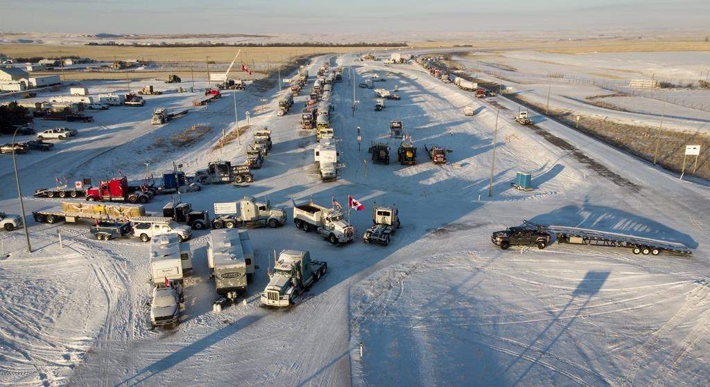 A truck convoy of anti-COVID-19 vaccine mandate demonstrators block the highway at the busy U.S. border crossing in Coutts, Alta., Wednesday, Feb. 2, 2022. A female undercover officer is set to continue her testimony Wednesday at a trial for two men charged with conspiracy to commit murder during the blockade.