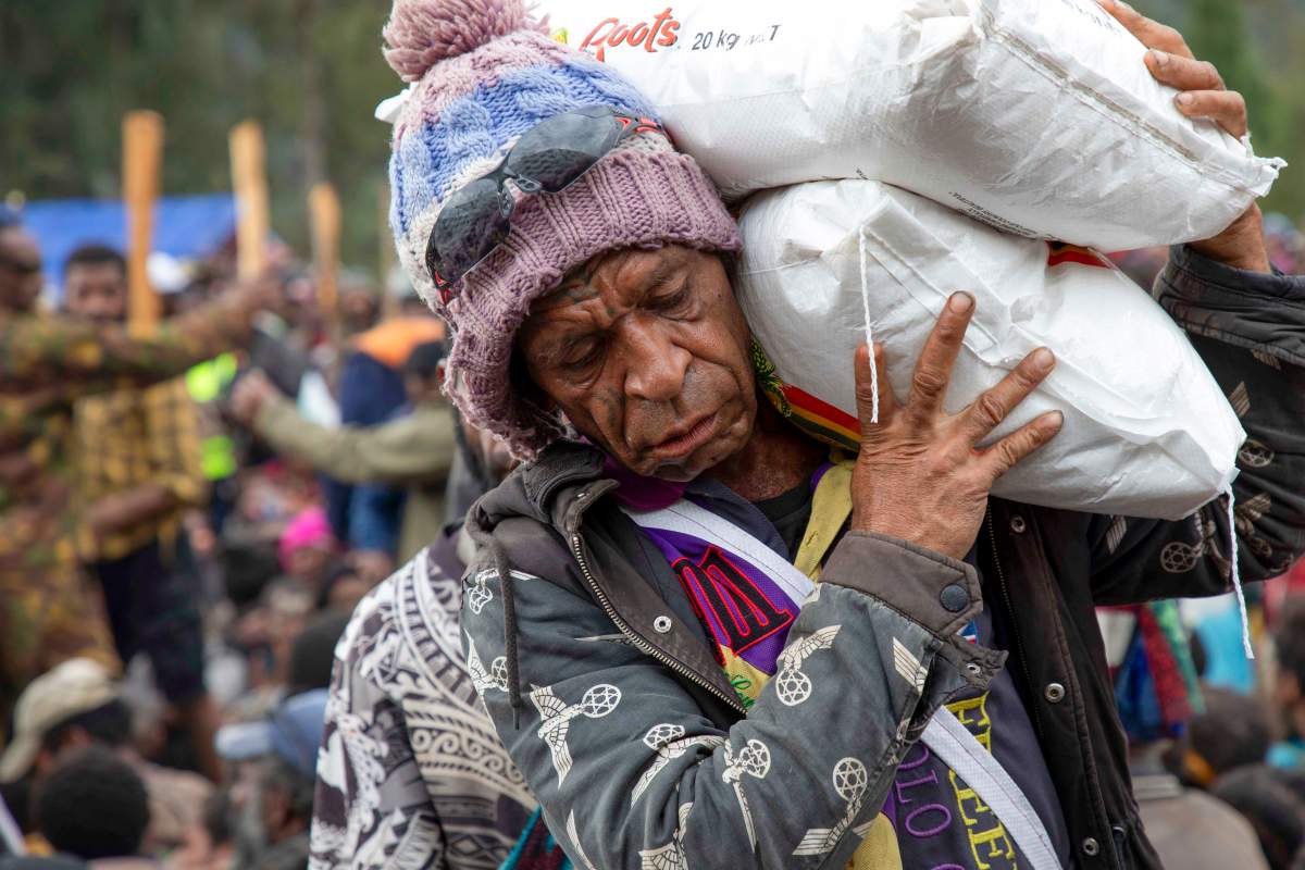 Villagers carry donated food aid at a temporary site for the displaced, following the May 24 landslide near Yambali village in the highlands of Papua New Guinea, Monday, June 3, 2024. (Juho Valta/UNDP Papua New Guinea)