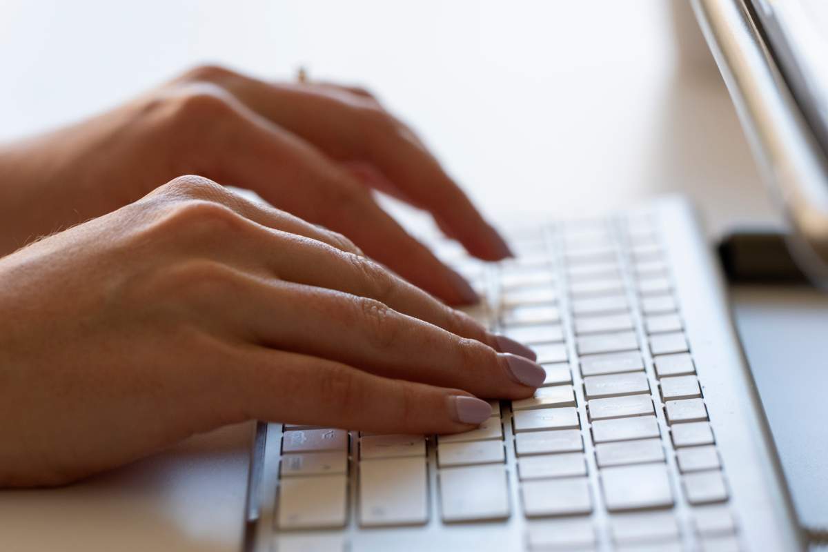 Hands type on a white keyboard.
