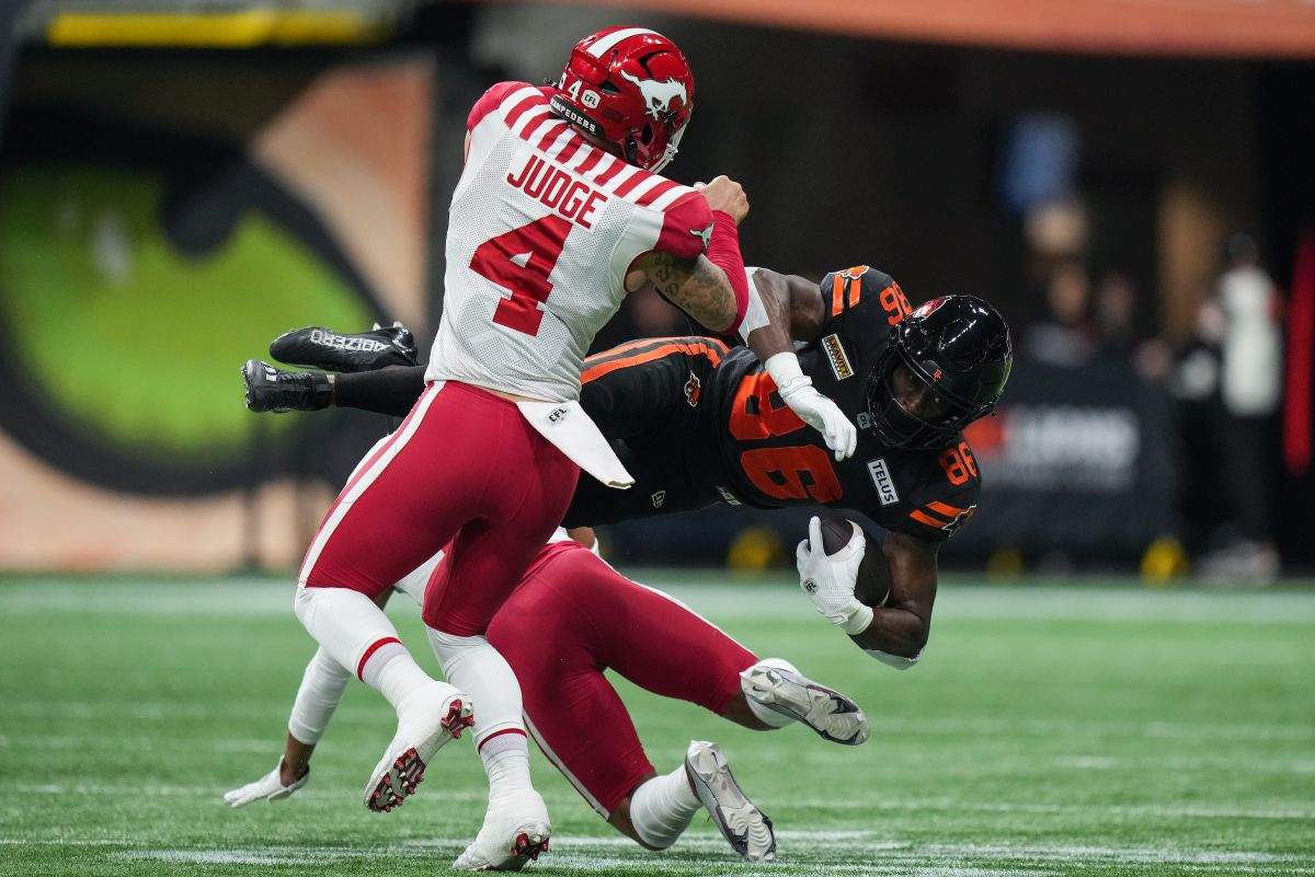B.C. Lions' Jevon Cottoy (86) is upended by Calgary Stampeders' Cameron Judge (4) and Jonathan Moxey, back, after making a reception during the first half of a CFL football game, in Vancouver, on Friday, October 20, 2023.