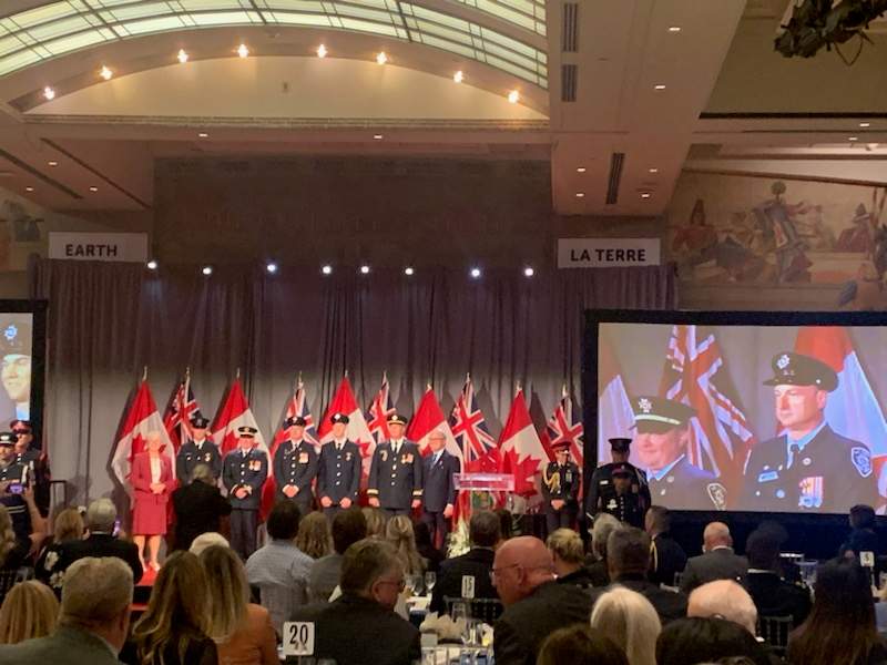 A group of firefighters in front of flags at an award ceremony.