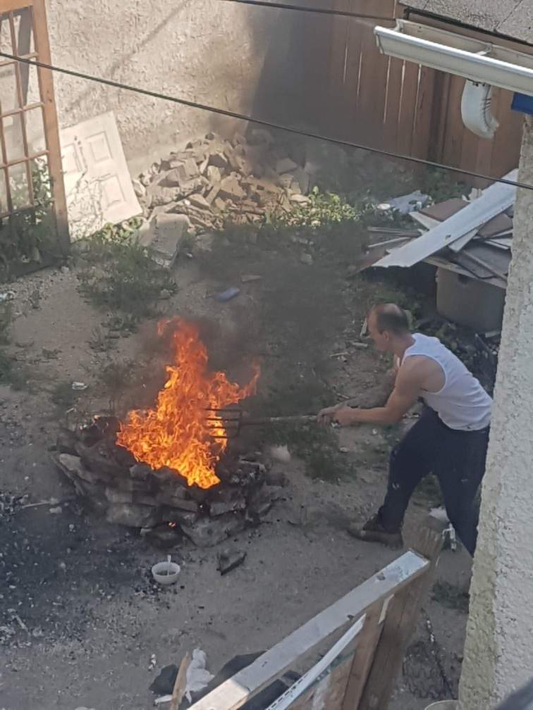 Man having open fire in backyard of vacant property.