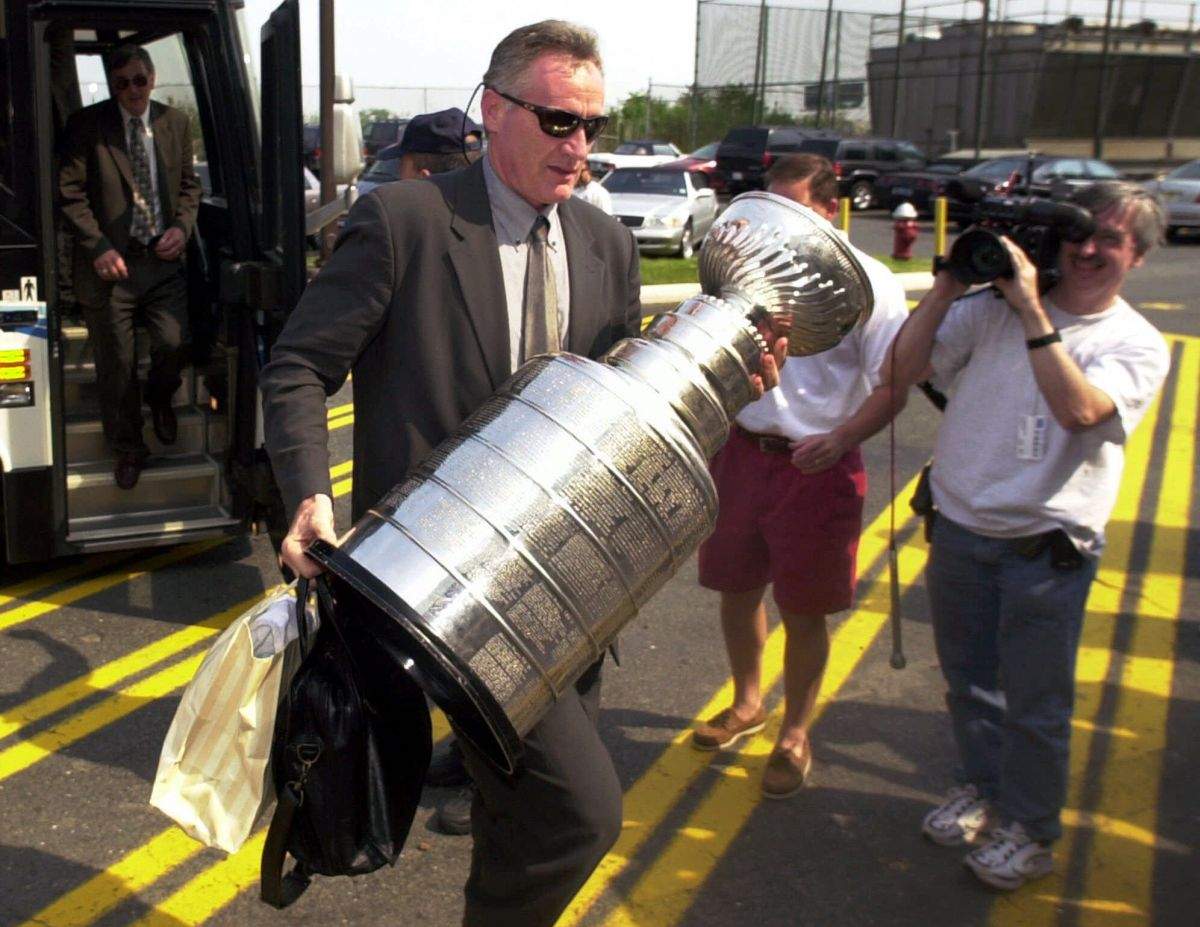 New Jersey Devils head coach Larry Robinson carries the Stanley Cup from the bus as the team arrives back at the Continental Airlines Arena in East Rutherford, N.J., Sunday, June 11, 2000. the Devils won the Stanley Cup after defeating the Dallas Stars 2-1 in the double overtime of Game 6 early Sunday morning.