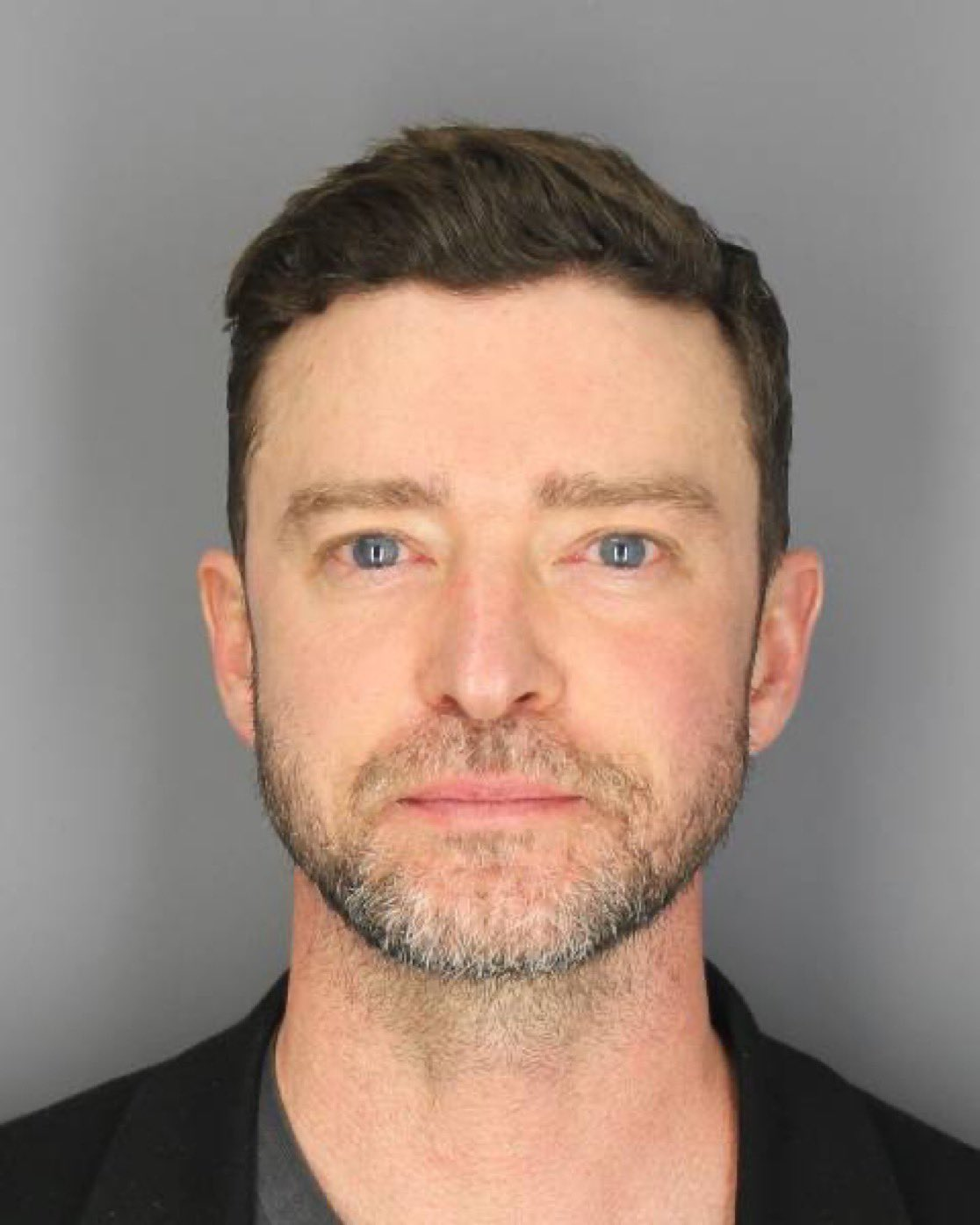 Justin Timberlake's mugshot. He is not smiling. His eyes are glassy and bloodshot.