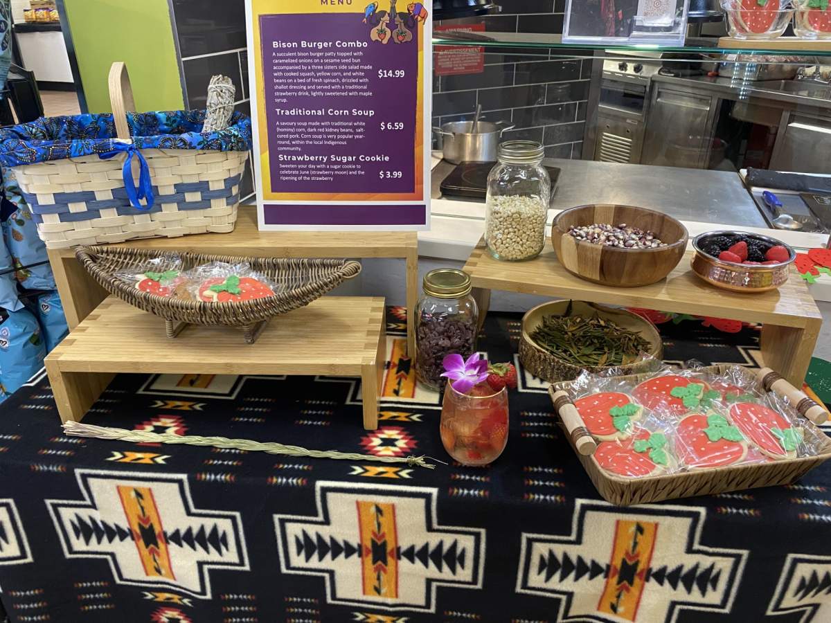 Strawberry cookies and drink on a table with herbs and beans with the menu in the back.