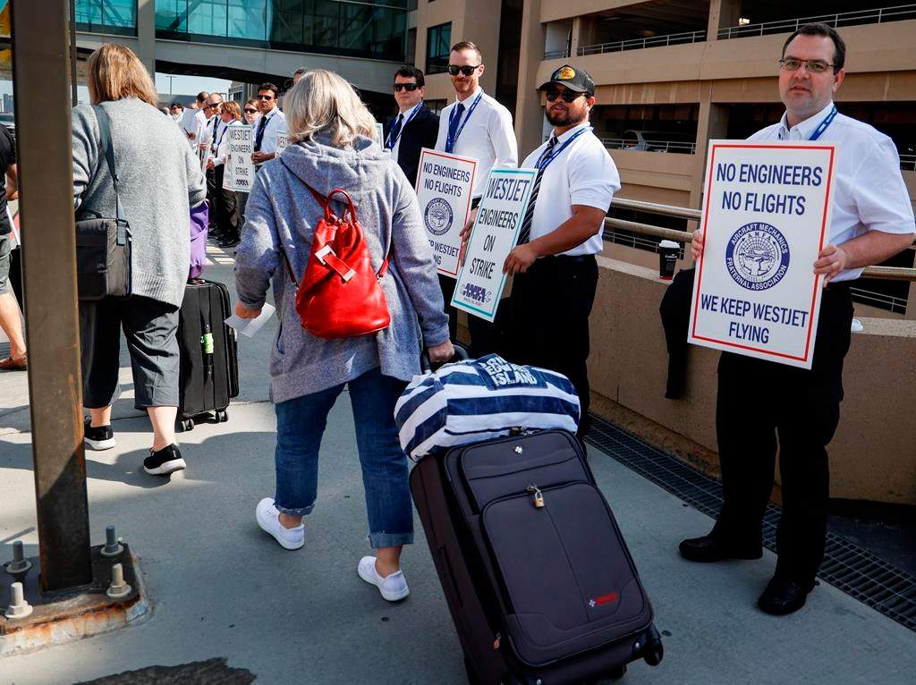 WestJet says there will still be flight disruptions, including cancellations, this week after a deal was reached to end a strike by its mechanics. Passengers make their way past striking WestJet mechanics at Calgary International Airport in Calgary, Saturday, June 29, 2024.
